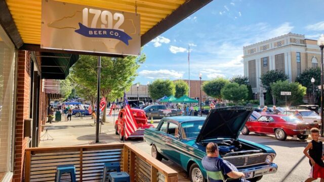 Classic cars parked on display outside a brewery