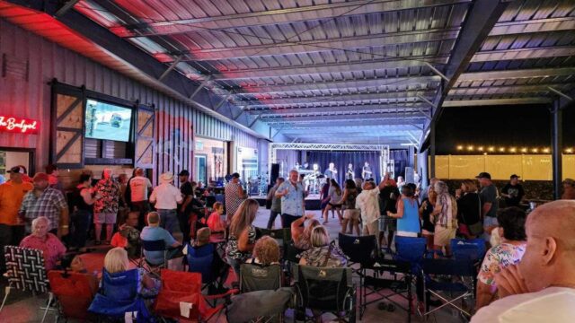 A crowd of people dancing and watching live musicians in an interior space