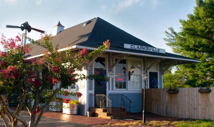 Exterior of a light blue clapboard building with brick steps leading up to the front door