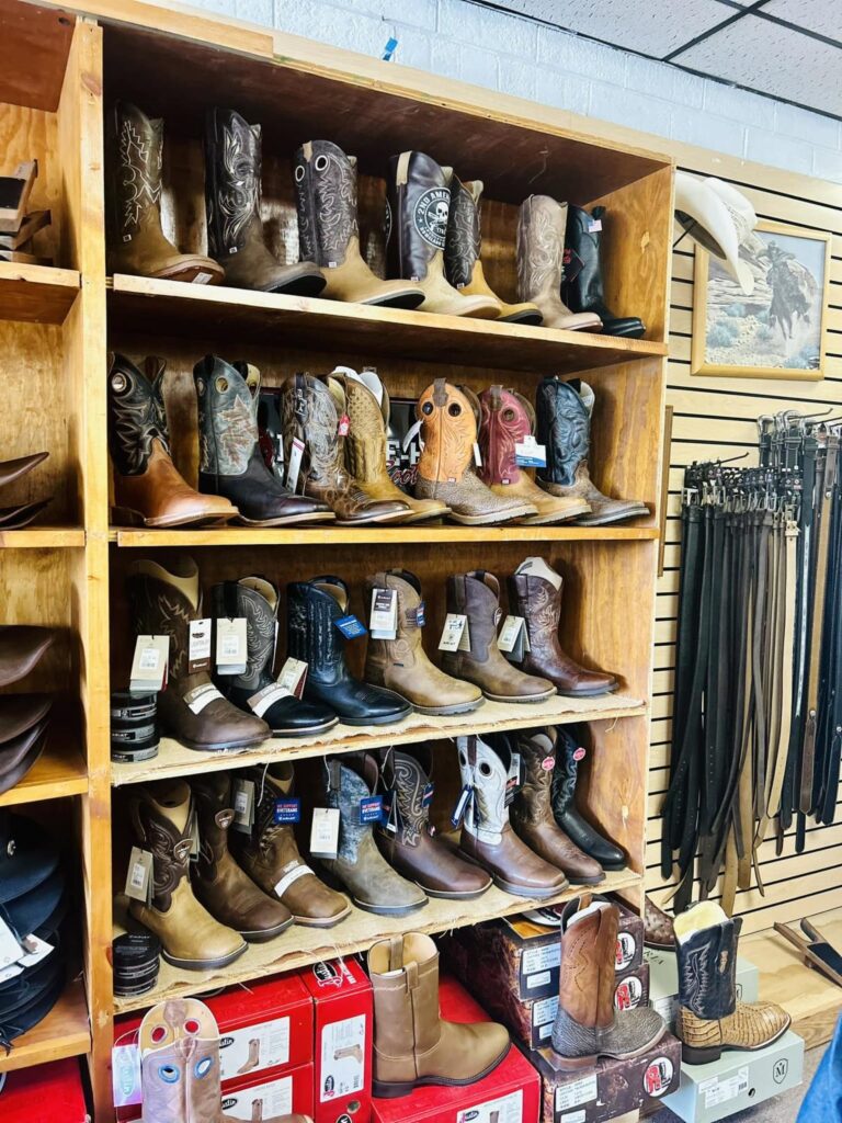 A wooden shelf with cowboy boots on display inside a store