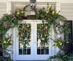 White double doors with glass panes are decorated with greenery and flowers