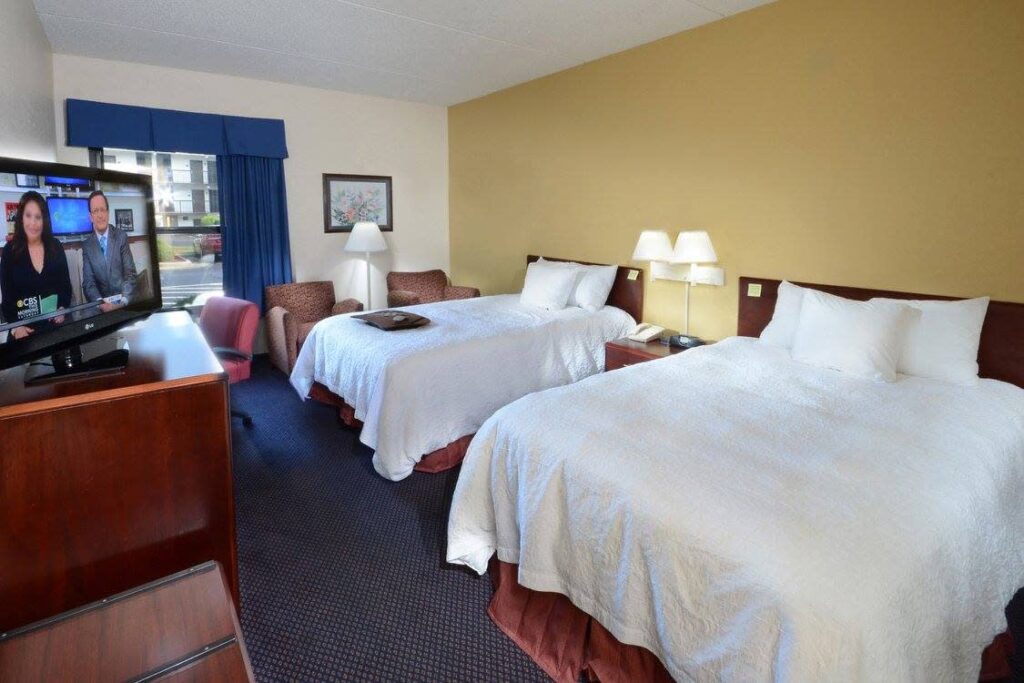 A hotel room with two queen size beds facing a TV