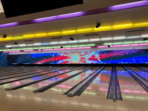 Empty lanes at a bowling alley with yellow and purple overhead lights